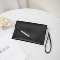 Elegant black envelope clutch with gold metal trim and wrist strap on white background - Black