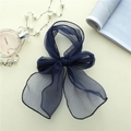 Detail der dunkelblauen Organza-Haarschleife mit feinen Rollkanten auf beigem Hintergrund - Marineblau