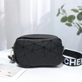 Black geometric patchwork crossbody bag with lettered strap in a lifestyle setting - Black