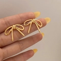 Primer plano de elegantes pendientes de lazo dorado mostrando la textura metálica - Pendientes de Botón Dorados con Lazo