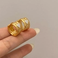 Nahaufnahme goldener Creolen mit Hammerschlag-Optik und weißen Herzanhängern - Goldene Herz Schnalle