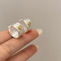 Detailaufnahme silberner Hammerschlag-Ohrringe mit einem strukturierten goldenen Herz - Silberne Herz Schnalle