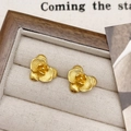 Detailopname van gouden bloemknopoorbellen met geborstelde textuur in een sieradendoos - Gouden Bloem Oorbellen