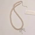 Detalle de collar de perlas con colgante de lazo plateado y cierre de mosquetón ajustable - Collar de Perlas con Colgante de Lazo Plateado
