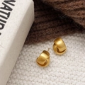 Nahaufnahme matter goldener Kreuzknoten-Ohrringe auf weißem Strickstoff-Hintergrund - Gebürsteter Kreuzstil (A-1135) / Gebürstetes Gold