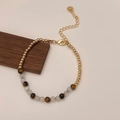 Detailweergave van tijgeroogkralen en gouden accenten op een verstelbare armband - Kristallen kralen armband