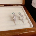 Macro detail of silver snake earrings with white zircons and green gemstone eyes - Silver