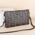 Detail view of a brown vintage crossbody bag with gold zipper and stylish printed pattern - Black base with Coffee