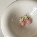 Detail van roze vierkante hanger oorbellen met gouden ringen in een witte keramieken kom - Roze