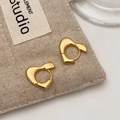 Close-up of golden irregular heart hoop earrings with a polished finish on beige fabric - Gold (Real Gold Plated)