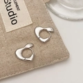 Detailed shot of chunky silver heart earrings on a textured beige fabric pouch - Silver (Gold Plated)
