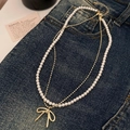 Double-layered pearl necklace with a gold bow pendant on a blue denim background - Double Layer Pearl Bowknot Necklace (Gold) / Gold