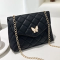 Elegant black quilted chain shoulder bag with creamy white butterfly clasp detail - Black