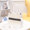Bolso tote blanco con estampados dorados y cinta a rayas sobre una mesa - Blanco