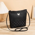 Chic black quilted bucket bag with a gold butterfly emblem and sleek shoulder strap - Black