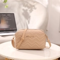 Elegant apricot quilted crossbody bag with golden logo on a white minimalist table - Khaki