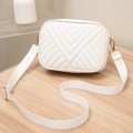 White crossbody bag featuring V-shaped quilting and wide nylon strap on wood surface - White