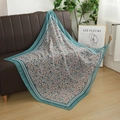 Detail view of floral print voile headscarf with teal geometric borders on a leather sofa - Lake Blue Geometric Border Floral Style (Style 5)