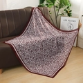 Detailed view of a 110cm square voile floral scarf displayed on a modern brown sofa - Burgundy Floral Style (Style 1)