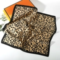 Detail of leopard print silk scarf draped over gift boxes with smooth satin texture - Leopard Style 14