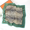 Dettaglio di un foulard in seta leopardato con bordi verdi su tessuto bianco operato - Stile Leopardo 3