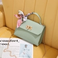 Mint green woven handbag with silk scarf and gold chain strap on yellow velvet sofa - Green