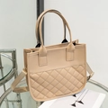 Quilted beige tote bag with a canvas strap displayed on a glass table in a modern setting - Khaki