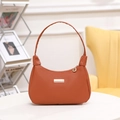 Bolso de media luna marrón caramelo minimalista con placa dorada en mesa blanca - Marrón