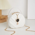 White quilted round crossbody bag with golden chain and cute black cat charm accessory - White