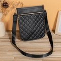 Black quilted crossbody bag with wide strap and golden zipper on wooden surface - Black