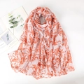 Détail d'une écharpe légère blanche avec motif baroque orange sur tissu en coton et lin - Rose