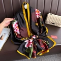 Elegant silk scarf with pink peonies and yellow border draped on a leather couch - One Size / Black