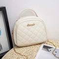 Quilted cream crossbody bag with gold chain strap and elegant hardware on woven mat - White