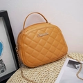 Chic yellow quilted crossbody bag with golden chain strap and top handle in a cozy setting - Yellow