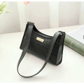 Detail of black embossed shoulder bag with golden metal plate on white surface - Black