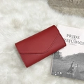 Red lychee textured envelope wallet for women with tassel charm on plush white carpet - Red