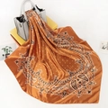 Detail eines Satin-Halstuchs mit Paisleymuster in Orange an einer grauen Handtasche - 90x90cm / Bernstein Paisley