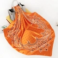 Detail eines orangefarbenen Satin-Tuchs mit Paisley-Muster über einer Ledertasche - 90x90cm / Orange Paisleymuster