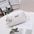 White quilted crossbody bag with gold hardware and wide fabric strap on a table - White
