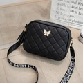 Detail of black quilted crossbody bag featuring a golden butterfly clasp and tassel charm - 18*6*13.5cm / Black