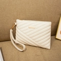 Detail of cream quilted clutch featuring gold hardware and removable wristlet strap - White