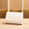 Quilted cream white crossbody bag with gold chain strap on a wooden surface - White