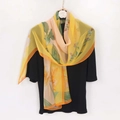 Elegante bufanda de georgette floral amarilla mostrada como chal sobre camisa negra - 160*50cm (Georgette) / Naranja
