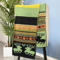 Détail d'une écharpe d'hiver en maille avec motifs jacquard de rennes, cœurs et flocons - Vert