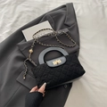 Bolso acolchado negro con asa de madera y cadena dorada sobre una chaqueta de traje gris - Negro