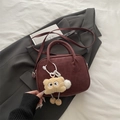 Donkerrode Boston tas van suède met pluche hanger op een grijs colbert gepresenteerd - Rood met hanger