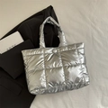 Metallic silver quilted tote bag with square stitching and glossy finish shown on lifestyle background - Silver