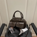 Vintage dunkelbraune Kissentasche mit Doppeltaschen und Goldbeschlägen auf einem Stuhl - Kaffeebraun