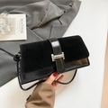 Minimalist black patchwork leather shoulder bag with silver H-buckle on grey suit background - Black