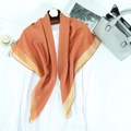 Orange-red long scarf with gold metallic trim draped on a white hanger for fashion - Earthy Orange